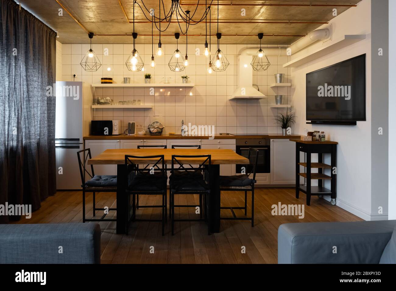 Moderne scandinave un décor intérieur de cuisine avec une grande table en bois et des chaises contre le sol en bois clair, des murs blancs lumineux et des meubles Banque D'Images