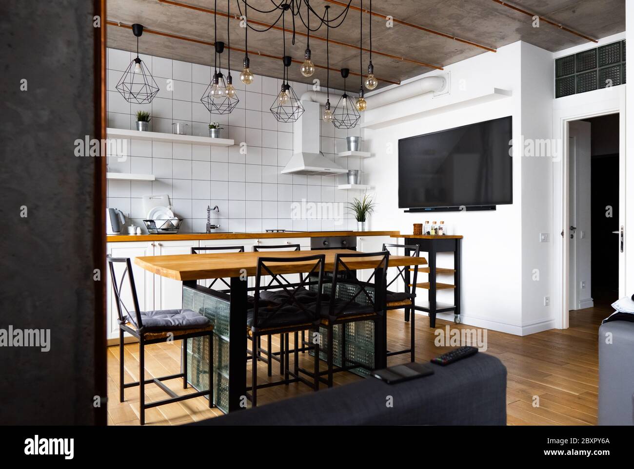 Moderne scandinave un décor intérieur de cuisine avec une grande table en bois et des chaises contre le sol en bois clair, des murs blancs lumineux et des meubles Banque D'Images