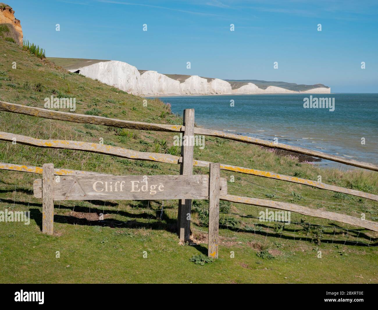 Seven Sisters falaises, East Sussex, Angleterre. Un panneau d'avertissement « Cliff Edge » sur la côte sud anglaise avec les falaises de craie blanches emblématiques visibles derrière. Banque D'Images