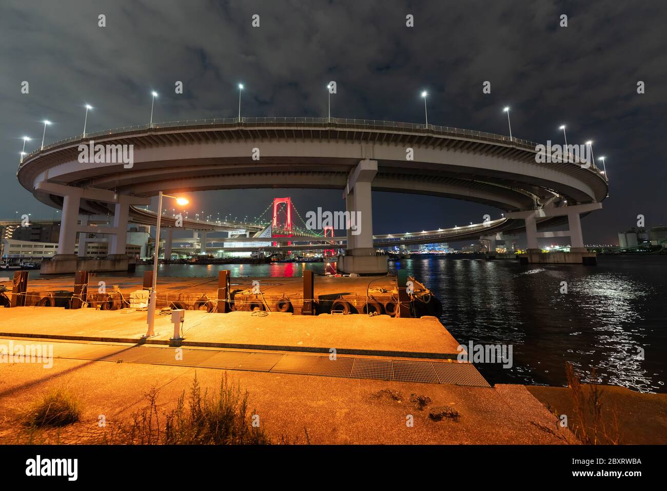 Vue nocturne du pont Rainbow, illuminé en rouge comme un signe de 'Tokyo Alert (alerte de coronavirus pour la région de Tokyo)' à Odaiba, Japon. Banque D'Images