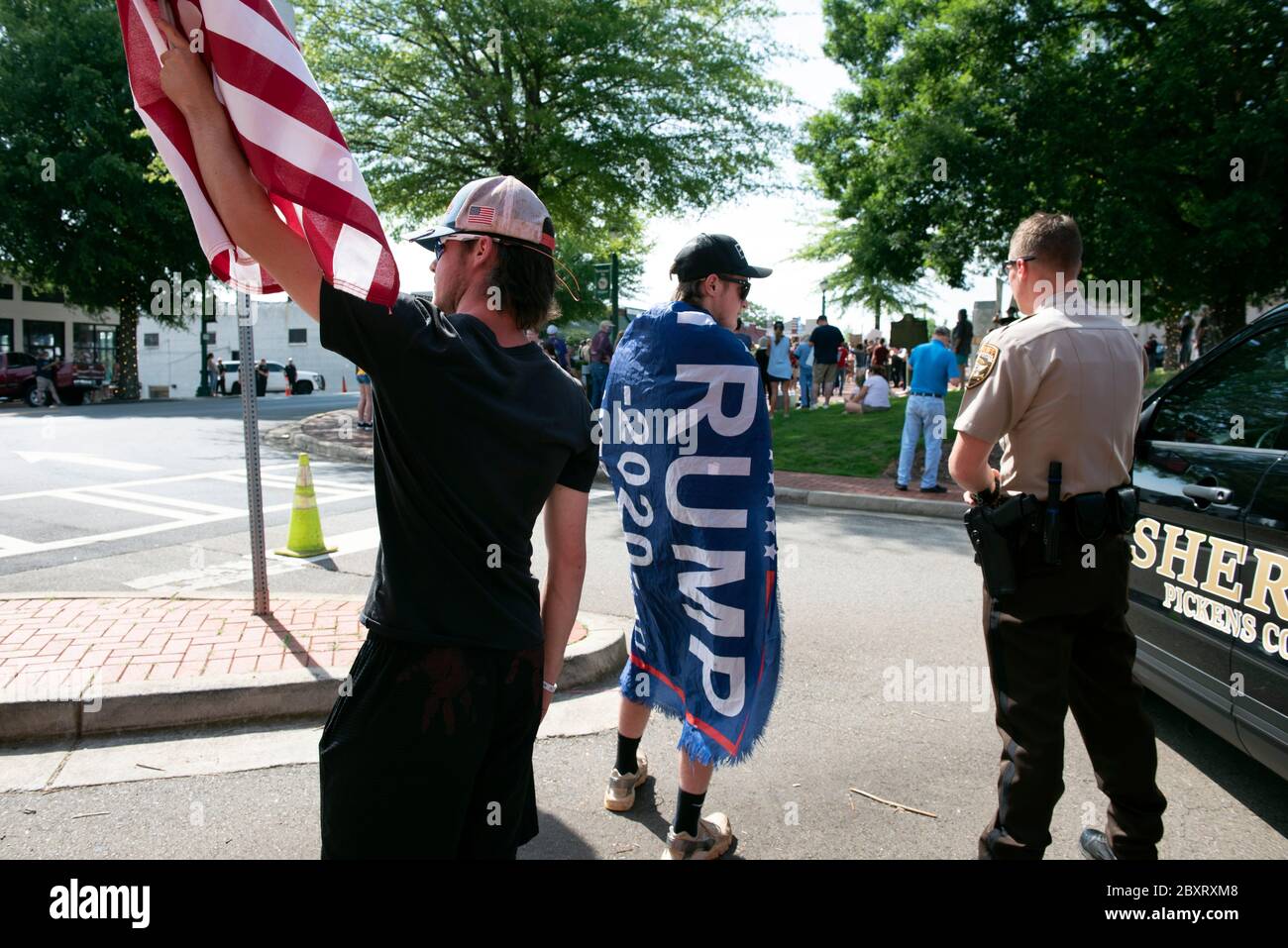 Jasper, Géorgie, États-Unis. 7 juin 2020. Les manifestants de Black Lives Matter se rassemblent à l'extérieur du palais de justice du comté de Pickens, dans la région rurale du nord de la Géorgie, pour protester contre la brutalité policière contre les minorités. Ils ont été accueillis par des contre-manifestants conservateurs et des partisans du président Trump qui ont assisté au rassemblement de l'autre côté de la rue principale de townÃs. Photo : les élèves du secondaire qui prévoient voter en novembre brandifient les drapeaux pour soutenir le président Trump alors que les voitures passent dans la rue principale de townÃs. Crédit : Robin Rayne/ZUMA Wire/Alay Live News Banque D'Images