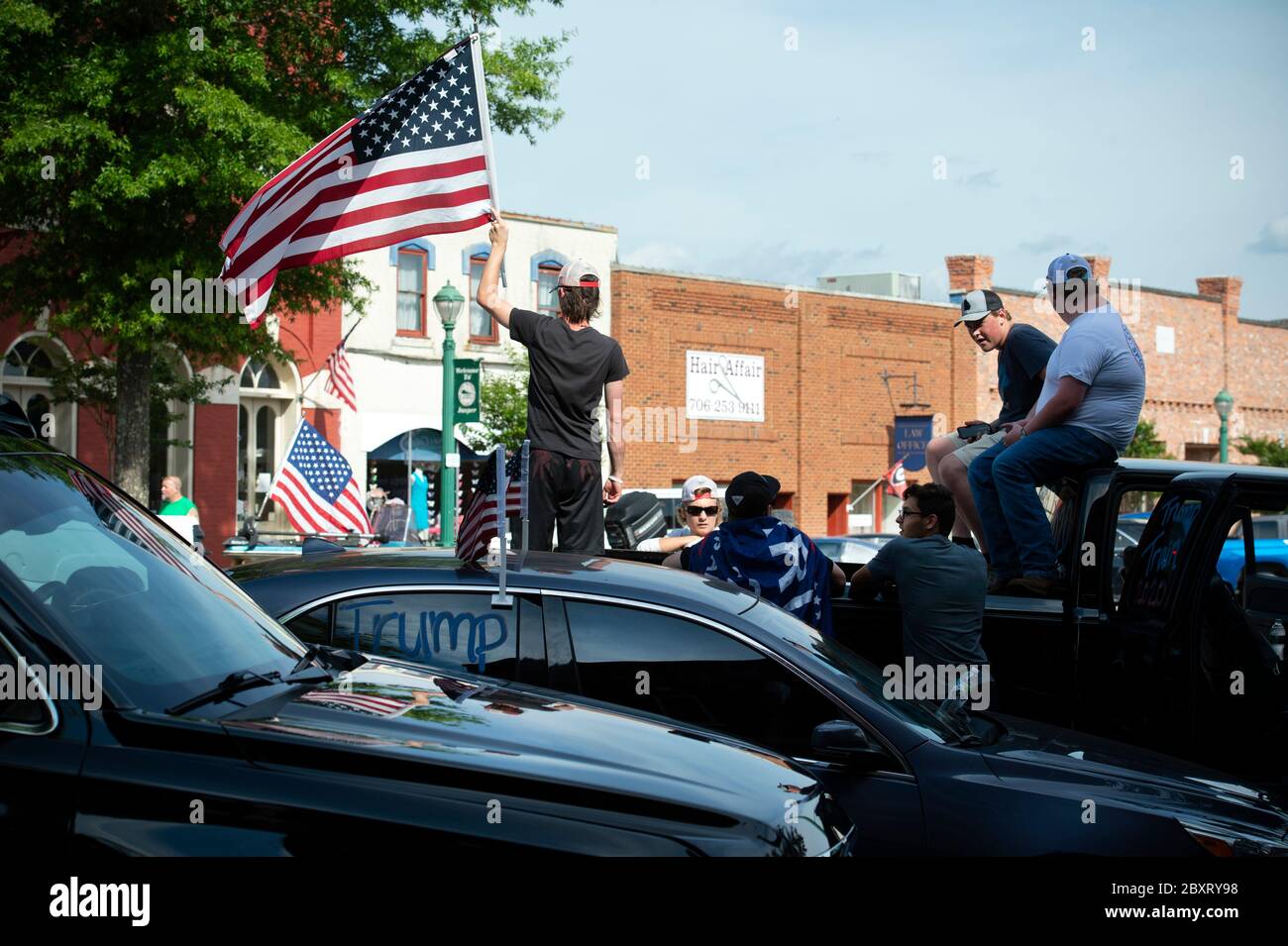 Jasper, Géorgie, États-Unis. 7 juin 2020. Les manifestants de Black Lives Matter se rassemblent à l'extérieur du palais de justice du comté de Pickens, dans la région rurale du nord de la Géorgie, pour protester contre la brutalité policière contre les minorités. Ils ont été accueillis par des contre-manifestants conservateurs et des partisans du président Trump qui ont assisté au rassemblement de l'autre côté de la rue principale de townÃs. Photo : les élèves du secondaire qui prévoient voter en novembre brandifient les drapeaux pour soutenir le président Trump alors que les voitures passent dans la rue principale de townÃs. Crédit : Robin Rayne/ZUMA Wire/Alay Live News Banque D'Images