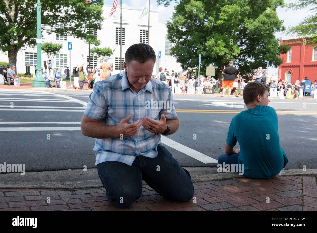 Jasper, Géorgie, États-Unis. 7 juin 2020. Les manifestants de Black Lives Matter se rassemblent à l'extérieur du palais de justice du comté de Pickens, dans la région rurale du nord de la Géorgie, pour protester contre la brutalité policière contre les minorités. Ils ont été accueillis par des contre-manifestants conservateurs et des partisans du président Trump qui ont assisté au rassemblement de l'autre côté de la rue principale de townÃs. Photo: Un homme local s'agenouille pour prier en face de BLM rallye crédit: Robin Rayne/ZUMA Wire/Alamy Live News Banque D'Images