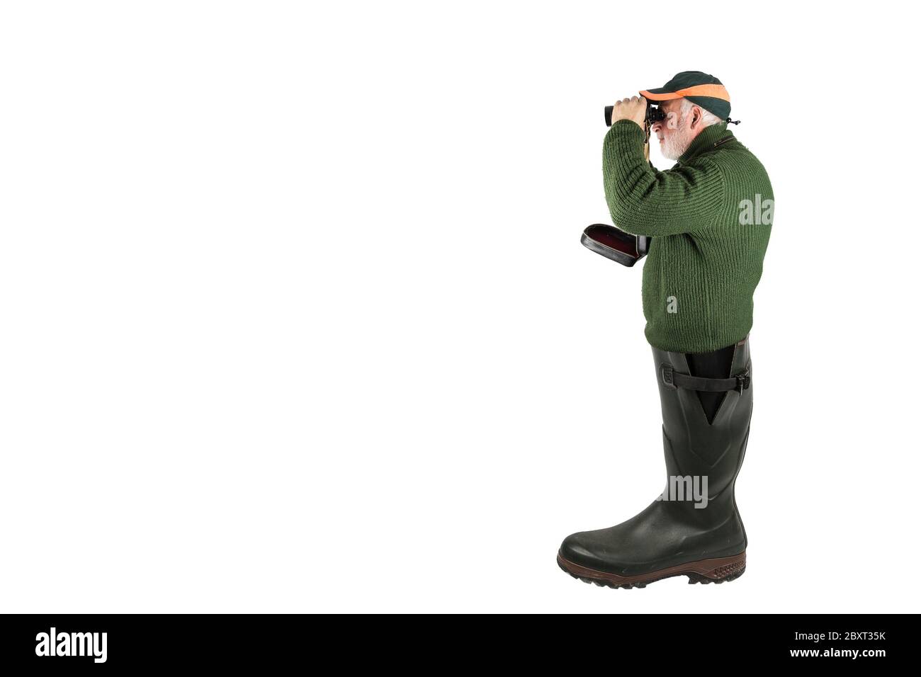 Un chasseur se tient dans une grande chaussure en caoutchouc et regarde à travers ses jumelles. Banque D'Images