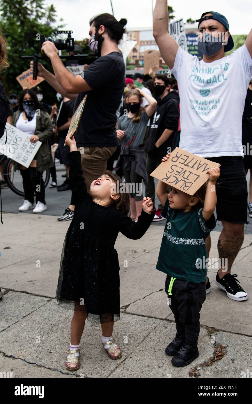 Un jeune garçon et une jeune fille avec des signes protestent lors d'une manifestation en l'honneur de George Floyd, dans le quartier Highland Park de Los Angeles, en Californie Banque D'Images