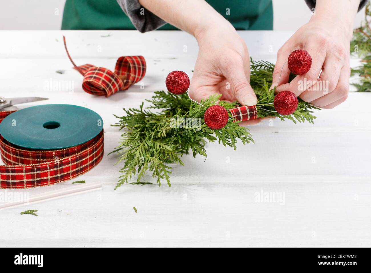 Fleuriste au travail: Comment faire des couronnes de porte de noël traditionnelles avec des brindilles de thuja. Étape par étape, tutoriel. Banque D'Images