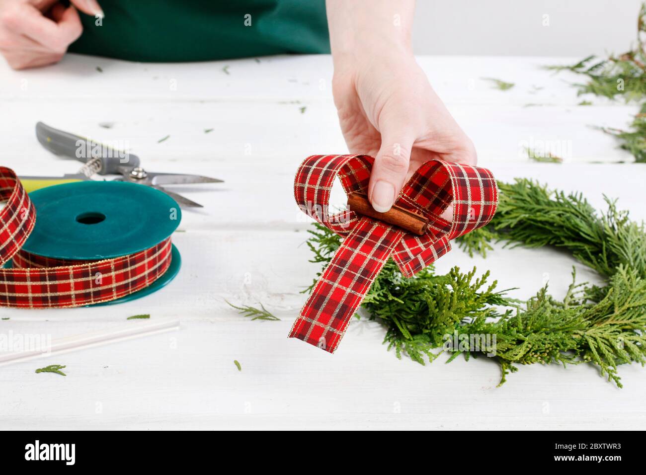 Fleuriste au travail: Comment faire des couronnes de porte de noël traditionnelles avec des brindilles de thuja. Étape par étape, tutoriel. Banque D'Images