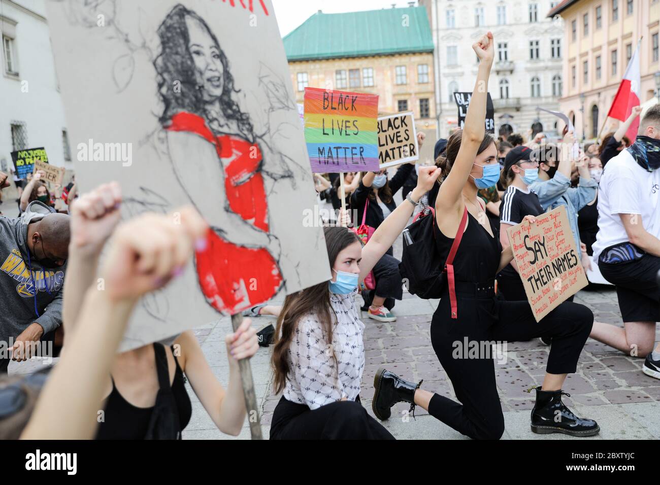 Les manifestants se tiennent un genou tandis qu'un autre tient en hauteur un écriteau représentant une femme afro-américaine pendant la manifestation Black Lives Matter.des centaines de jeunes ont participé à la manifestation « Black Lives Matter » à Cracovie, la plus grande ville du sud de la Pologne. Ils ont rendu hommage à George Floyd et ont exprimé leur désapprobation de la brutalité policière et du racisme. Banque D'Images