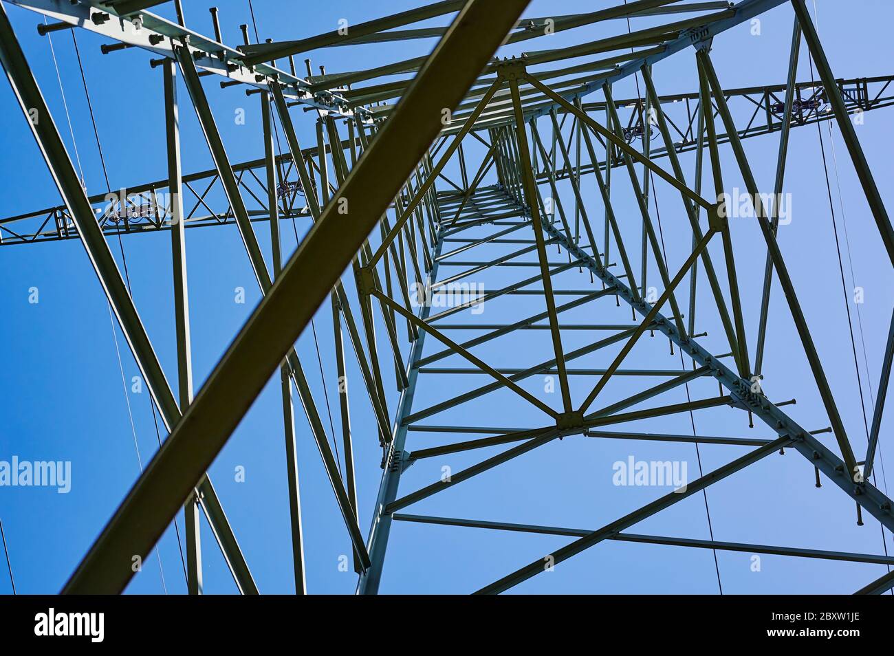 Photo à angle bas d'en dessous jusqu'au sommet d'un pylône électrique contre le ciel bleu. Banque D'Images