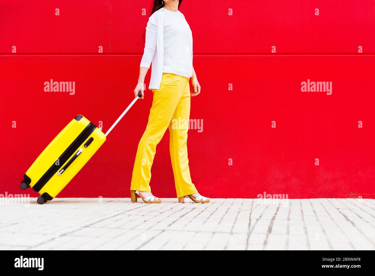 femme avec une valise jaune qui se promette dans la rue. Banque D'Images