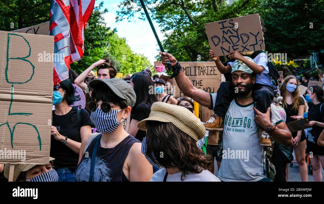 Petite fille tenant un panneau assis sur les épaules de son père dans une marche de protestation de famille à Brooklyn Banque D'Images