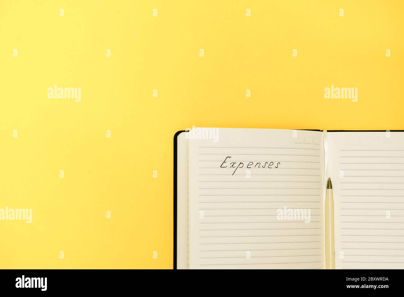 Concept de planification des dépenses et du budget. Vue de dessus du bloc-notes avec des mots manuscrits dépenses sur fond jaune avec espace de copie Banque D'Images