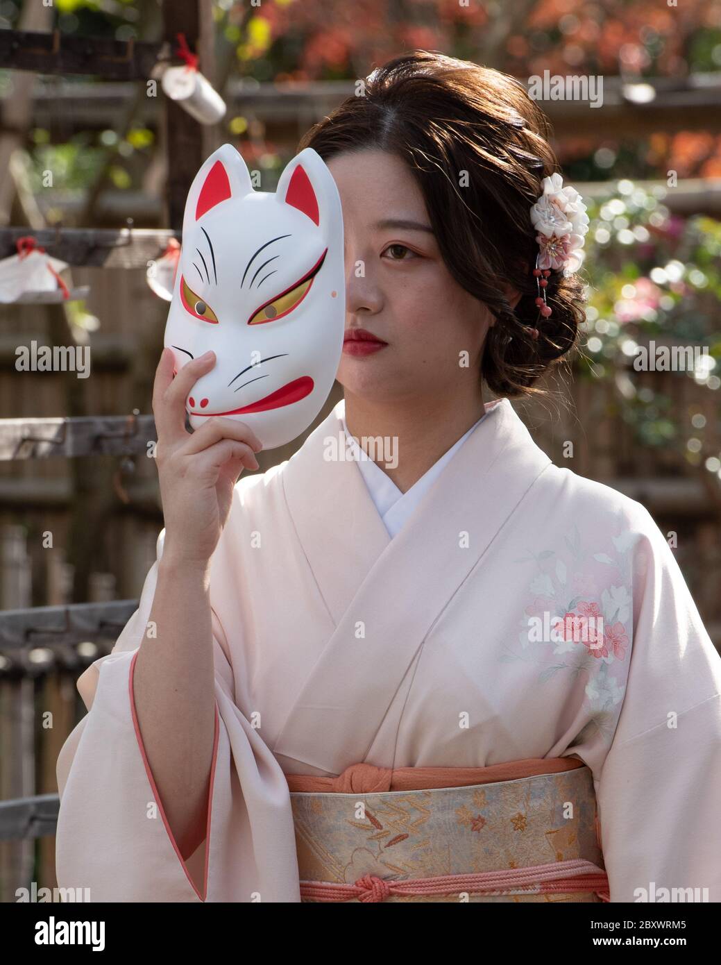 L'adolescent japonais portant un kimono traditionnel pose avec un masque de  kitsune. Masque de renard japonais. Ces masques sont portés pour le  plaisir, lors des festivals et pour honorer les dieux Photo