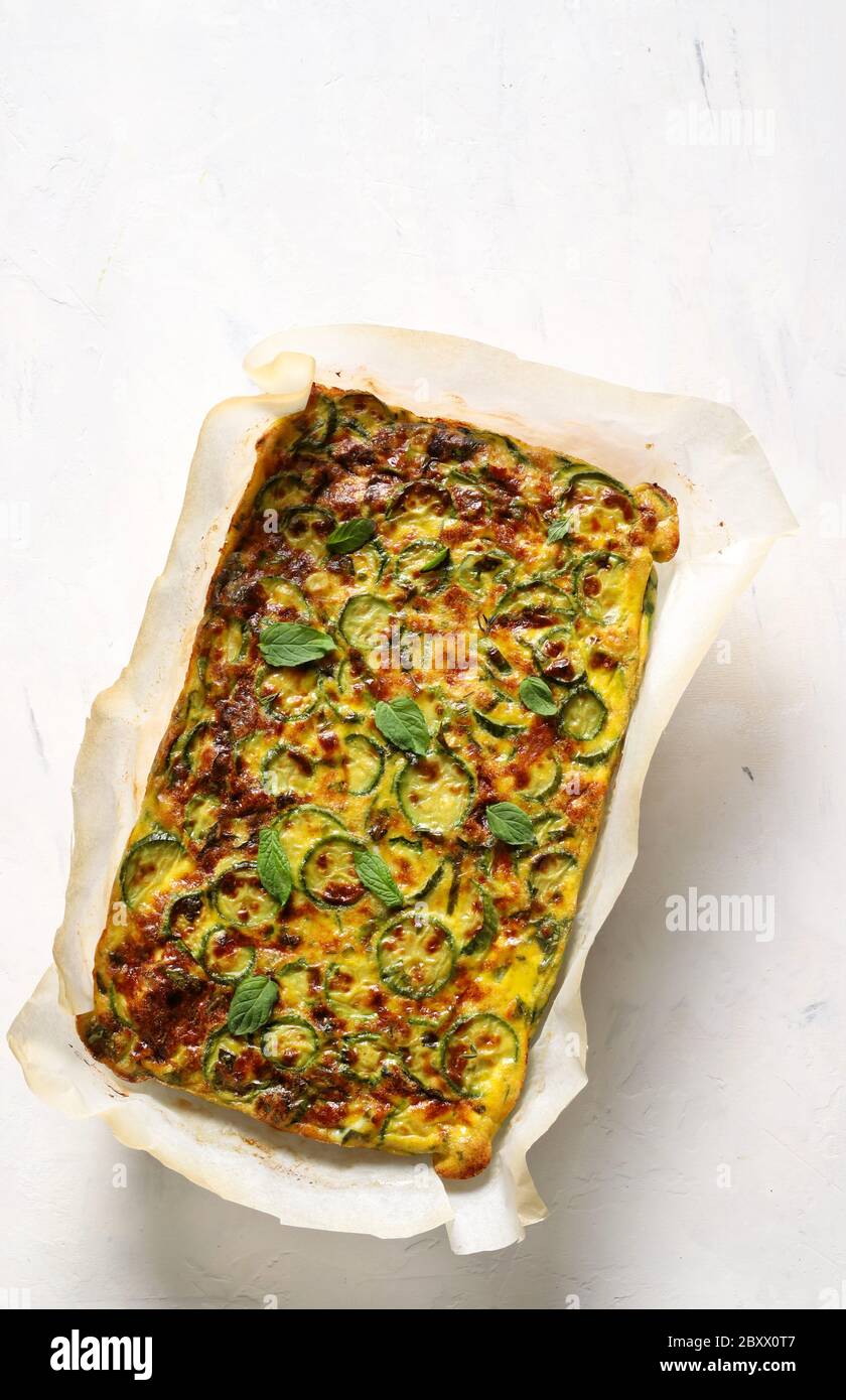 Concept alimentaire. Omelette cuite au four avec courgettes, poireaux et fromage isolés sur fond blanc. Vue de dessus. Banque D'Images