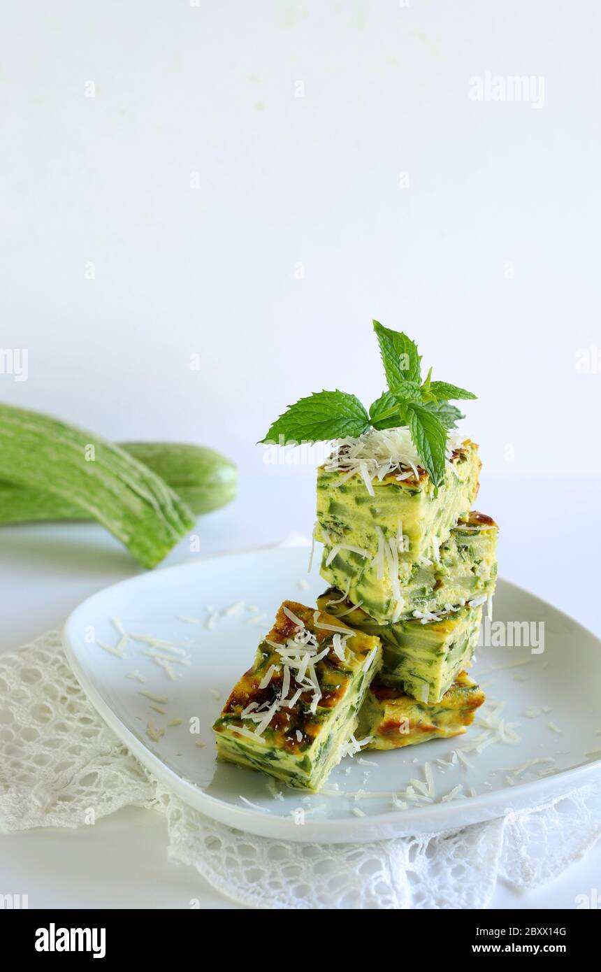 Concept alimentaire de printemps. Courgettes maison et frittata de poireaux arrosées de parmesan, saveur de menthe. Gros plan. Fond blanc. Banque D'Images