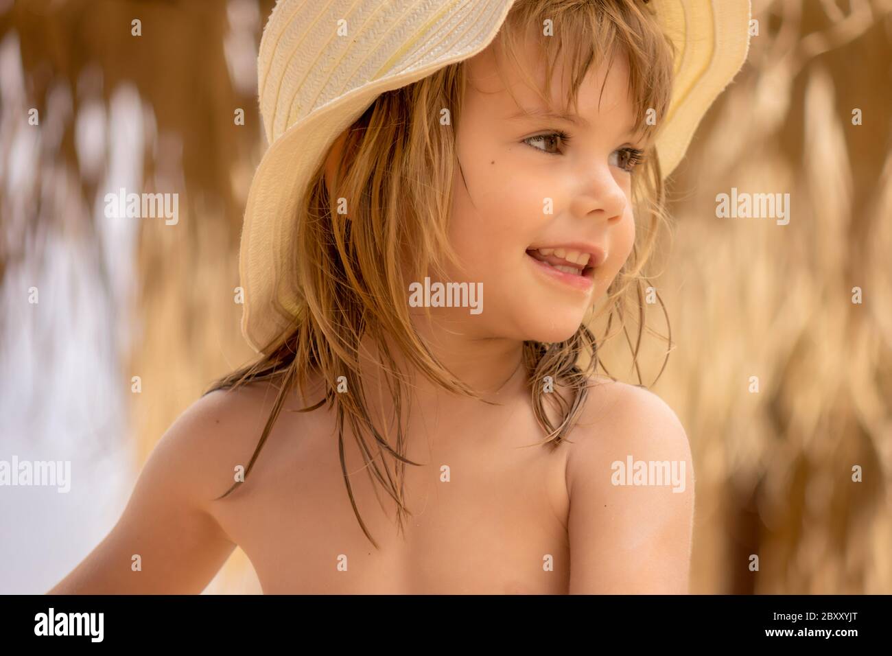 une petite fille avec un chapeau sur la plage Banque D'Images