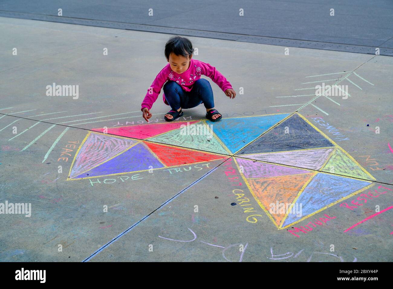 Jeune fille asiatique, explore le travail d'art de craie en forme de coeur à l'extérieur de la galerie Polygon, North Vancouver, Colombie-Britannique, Canada Banque D'Images