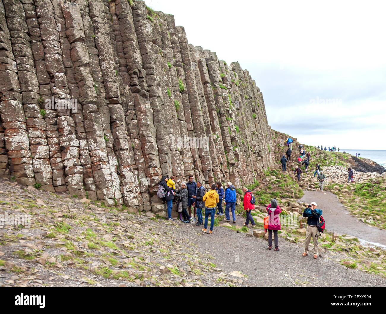 Les gens explorant les milliers d'anciennes colonnes de basalte imbriquées de la chaussée des géants sur la côte nord du comté d'Antrim, en Irlande du Nord. Banque D'Images