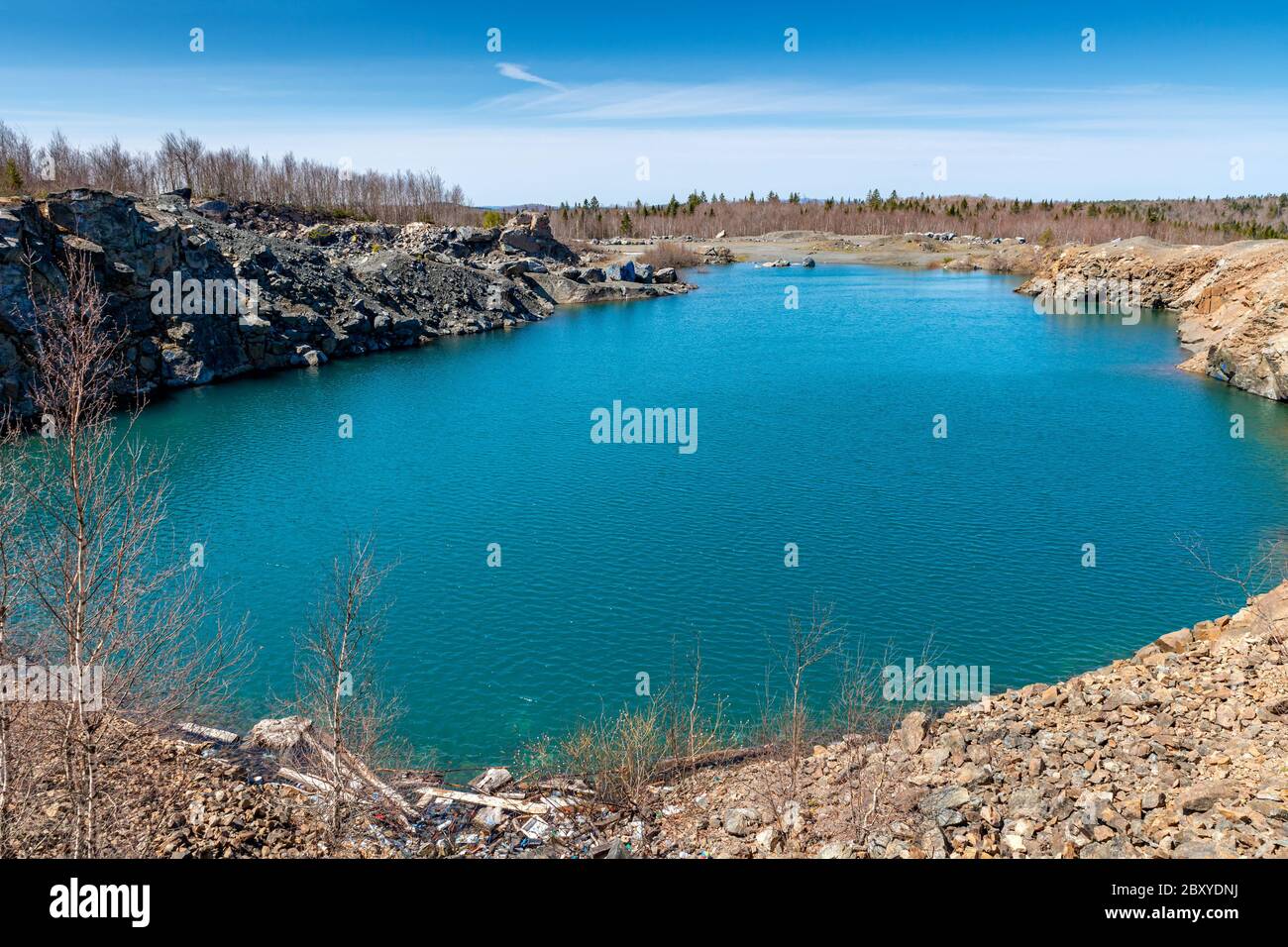 Une vieille carrière remplie d'eau, ce qui en fait un étang. L'eau est vert bleuâtre, avec le ciel au-dessus. Banque D'Images