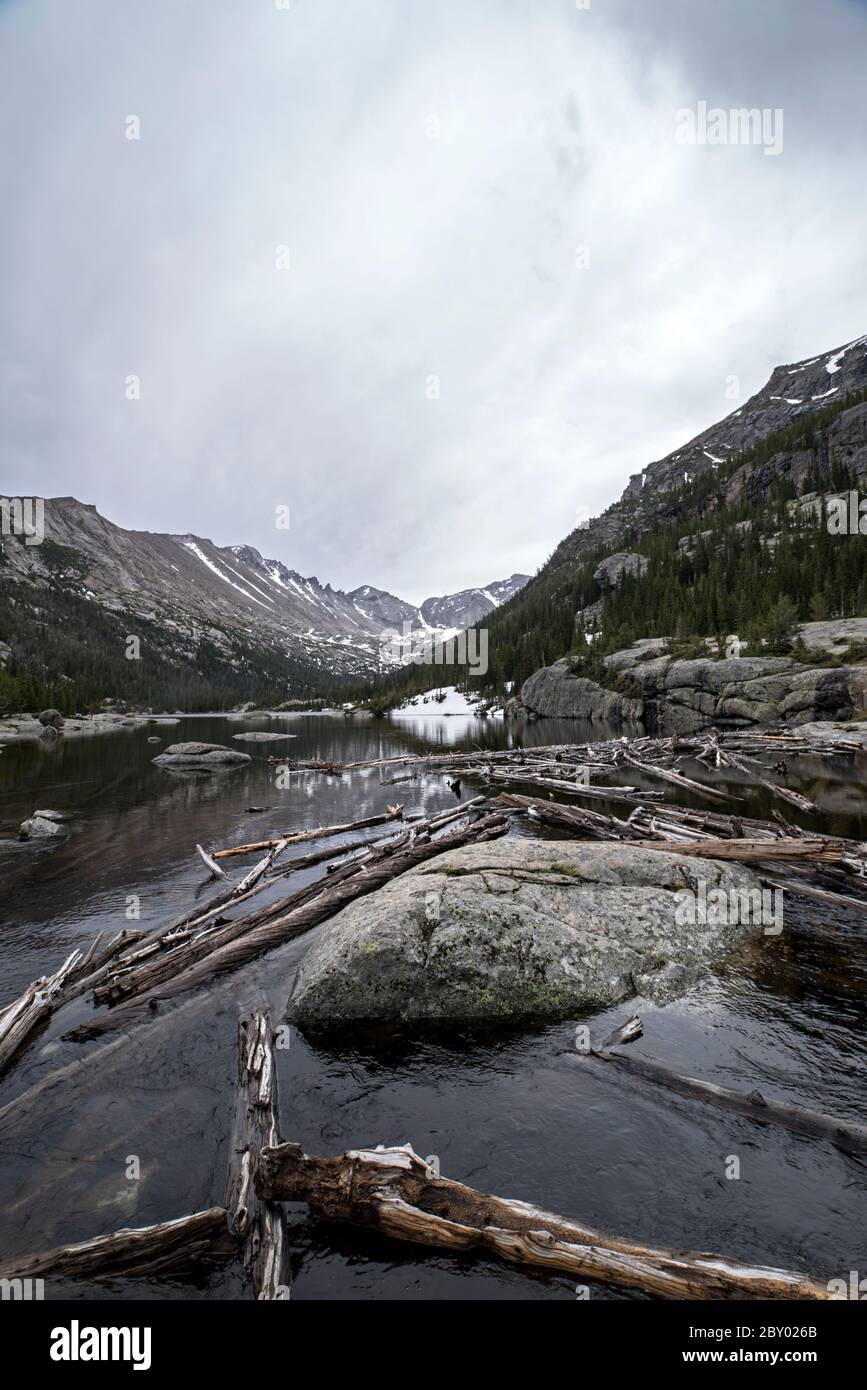 Lac alpin de Mill's Pond dans le parc national des montagnes Rocheuses avec un rocher, un arbre ou un moudefall dans le parc forestier et nuages et montagnes en arrière-plan Banque D'Images