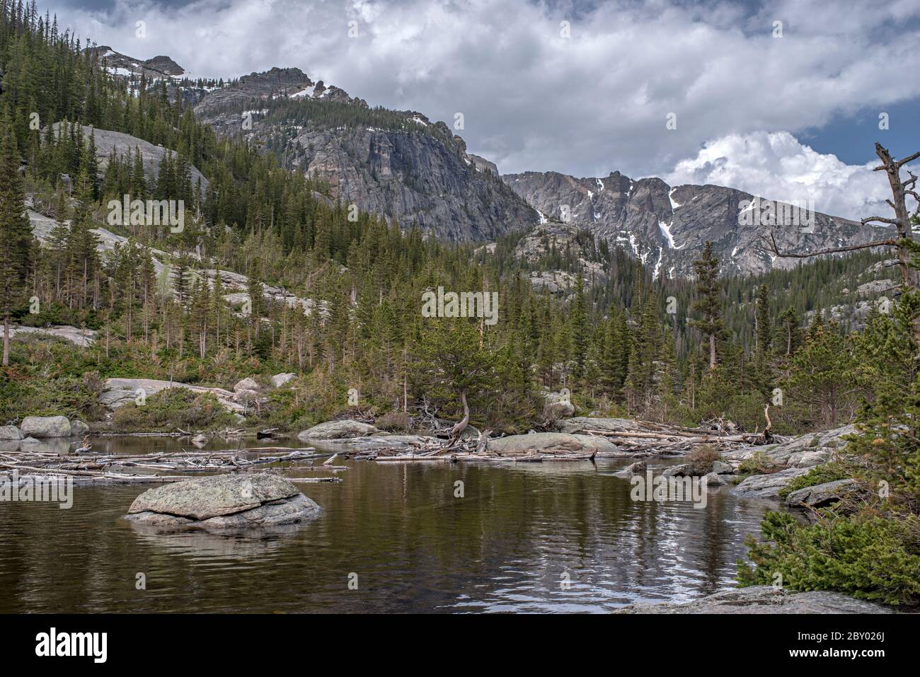 Lac alpin de Mill's Pond dans le parc national des montagnes Rocheuses avec un rocher, un arbre ou un moudefall dans le parc forestier et nuages et montagnes en arrière-plan Banque D'Images