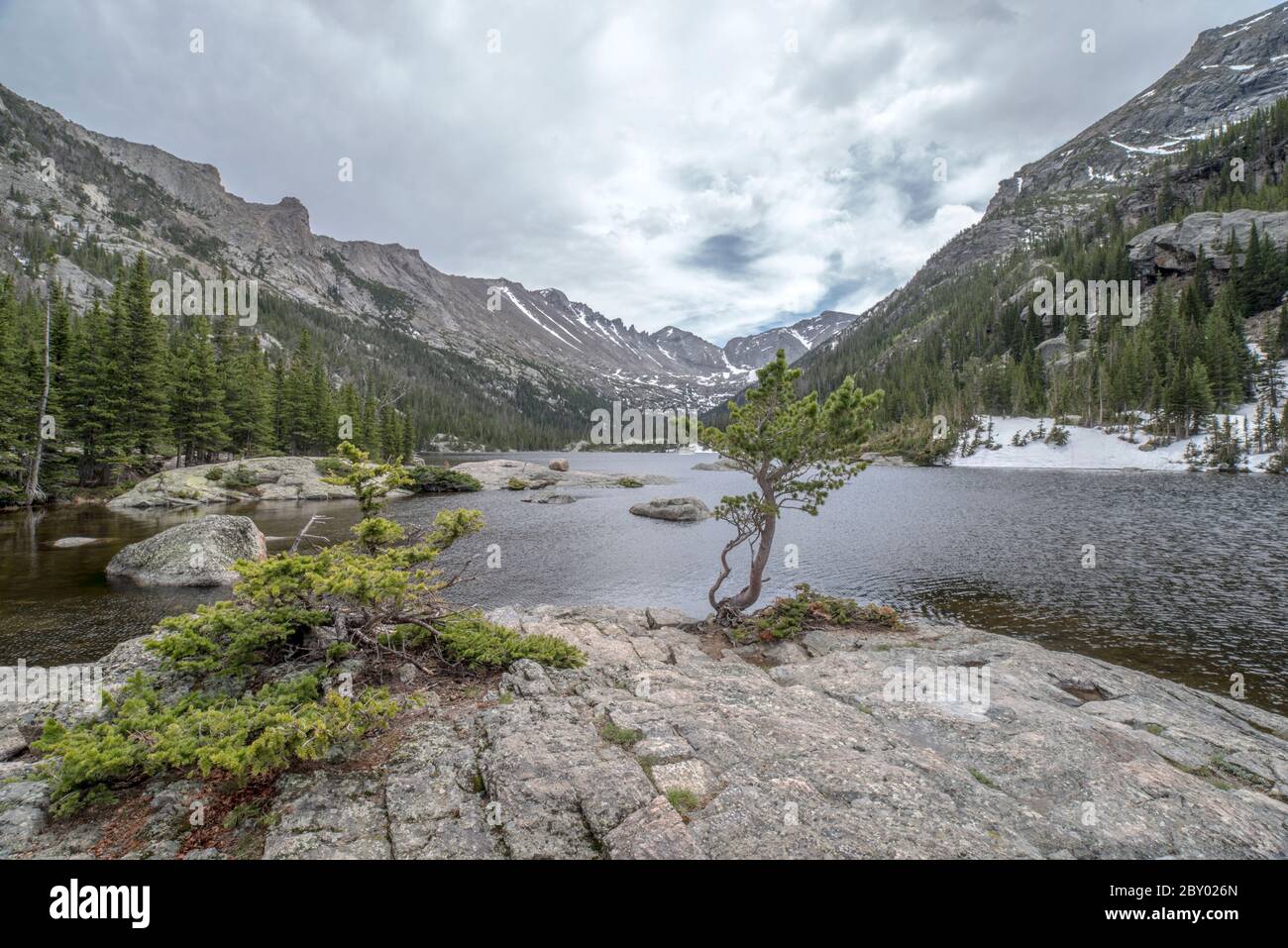 Lac alpin de Mill's Pond dans le parc national des montagnes Rocheuses avec un rocher, un arbre ou un moudefall dans le parc forestier et nuages et montagnes en arrière-plan Banque D'Images