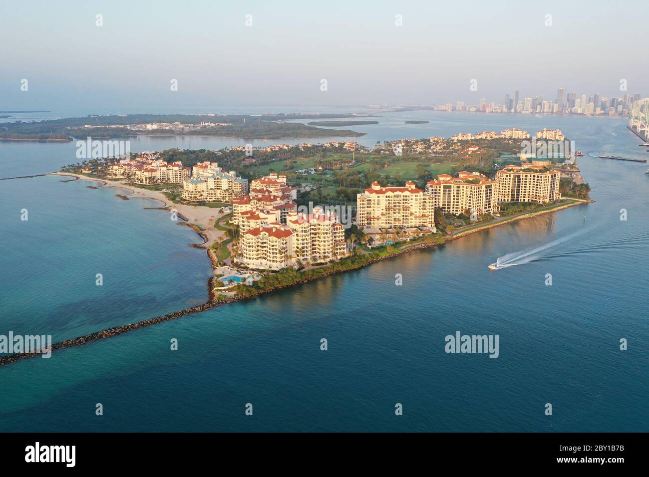 Vue aérienne de Fisher Island et de Government Cut avec vue sur la ville de Miami et Port Miami en arrière-plan au lever du soleil. Banque D'Images