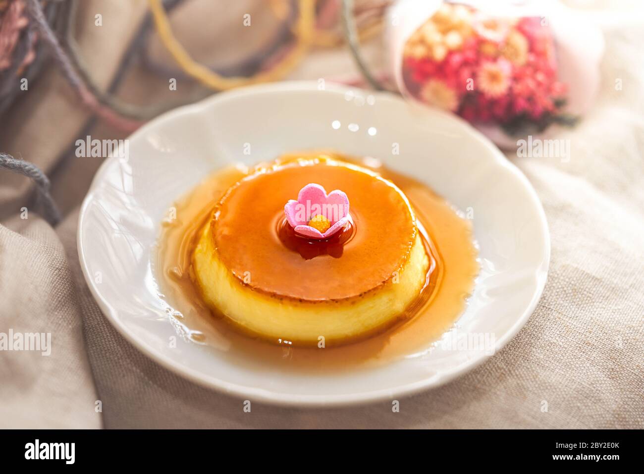 Pudding à la crème anglaise au caramel maison sur une assiette blanche et un tissu brun Banque D'Images