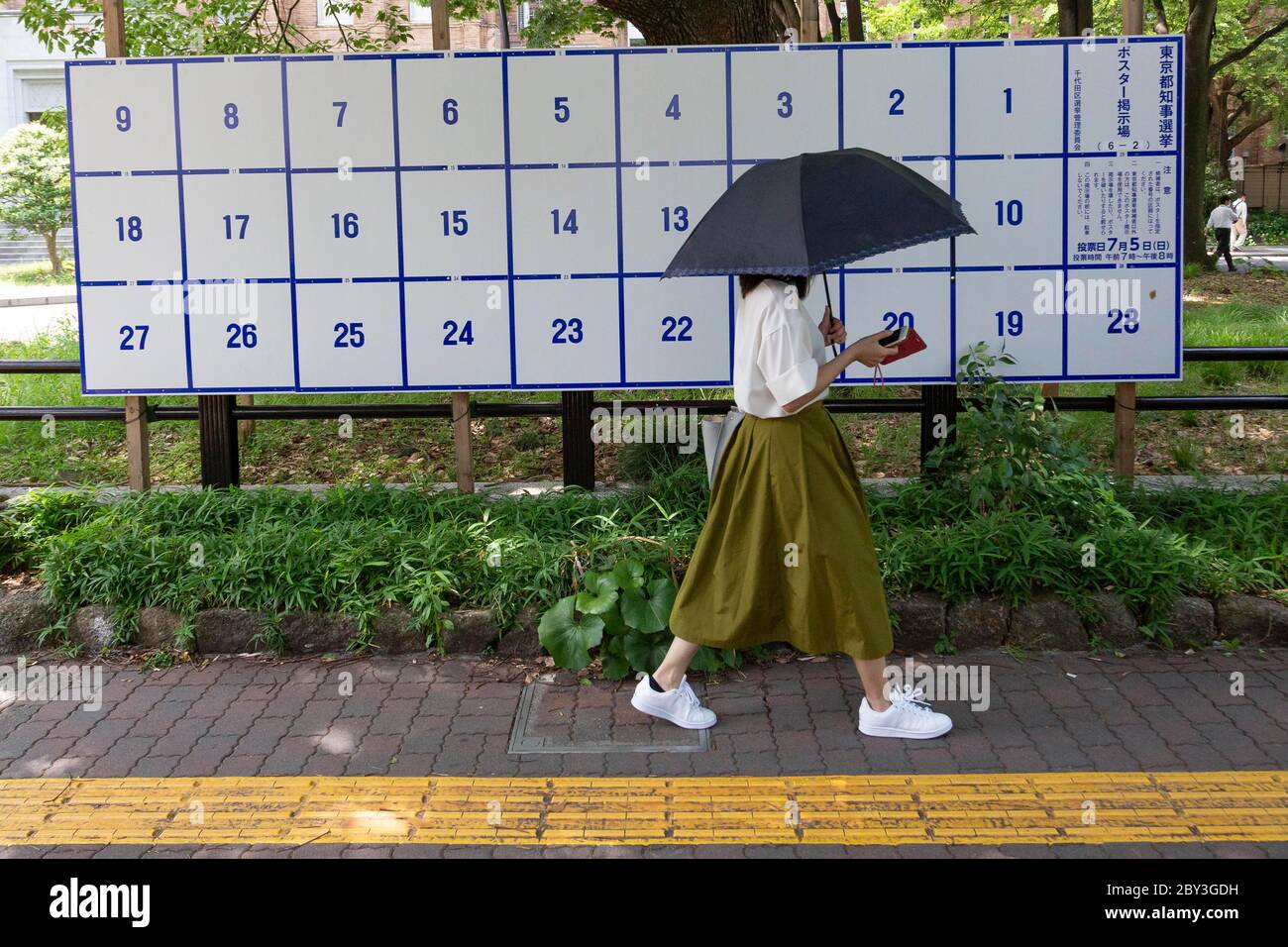 Une femme tenant un parapluie passe devant un panneau d'affichage érigé spécialement pour les affiches des candidats pour l'élection du gouverneur de Tokyo le 5 juillet, le 9 juin 2020, Tokyo, Japon. La période de campagne commence officiellement le 18 juin. Credit: Rodrigo Reyes Marin/AFLO/Alay Live News Banque D'Images