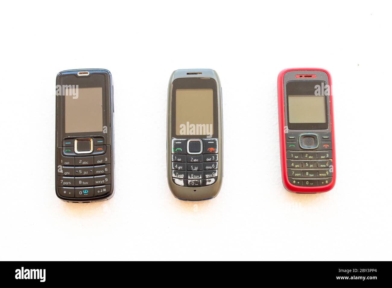 trois téléphones portables plus anciens appuyez sur le bouton de l'ancienne génération disposition modèle de pose sur fond blanc Banque D'Images