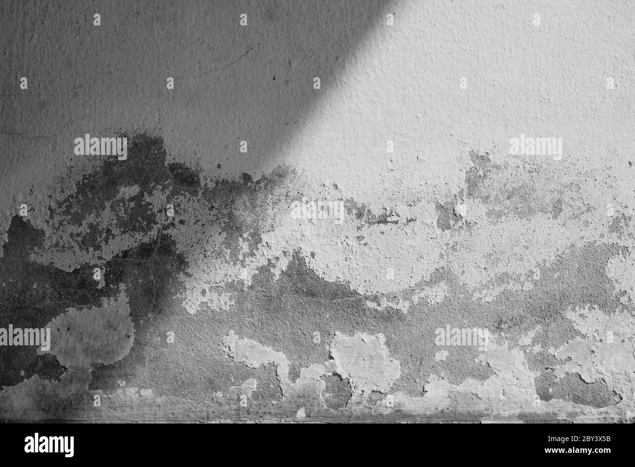 Close-up de ciment blanc fissure mur et peinture pelée causée par l'eau et de la lumière du soleil. Mur de Peel avec peinture maison blanche tache noire. Noir et blanc de Banque D'Images