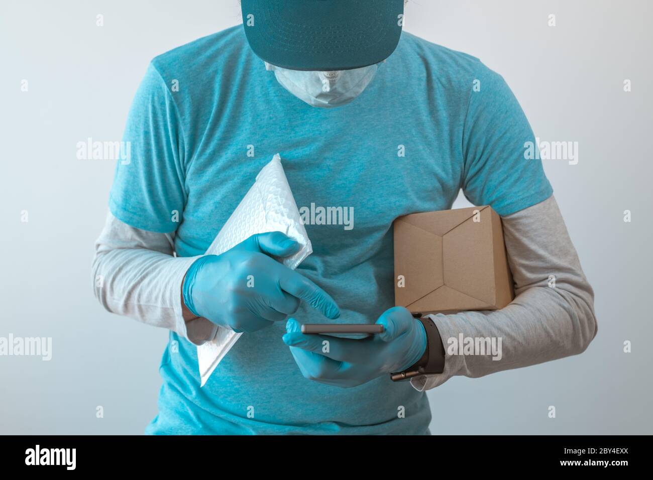 Homme de livraison avec des vêtements de protection utilisant un smartphone avec des gants de protection pendant une pandémie d'infection virale, foyer sélectif Banque D'Images