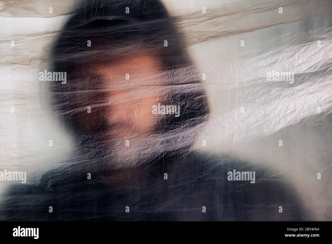 Concept de toxicomanie, homme flou avec hoodie derrière un rideau en plastique, foyer sélectif Banque D'Images