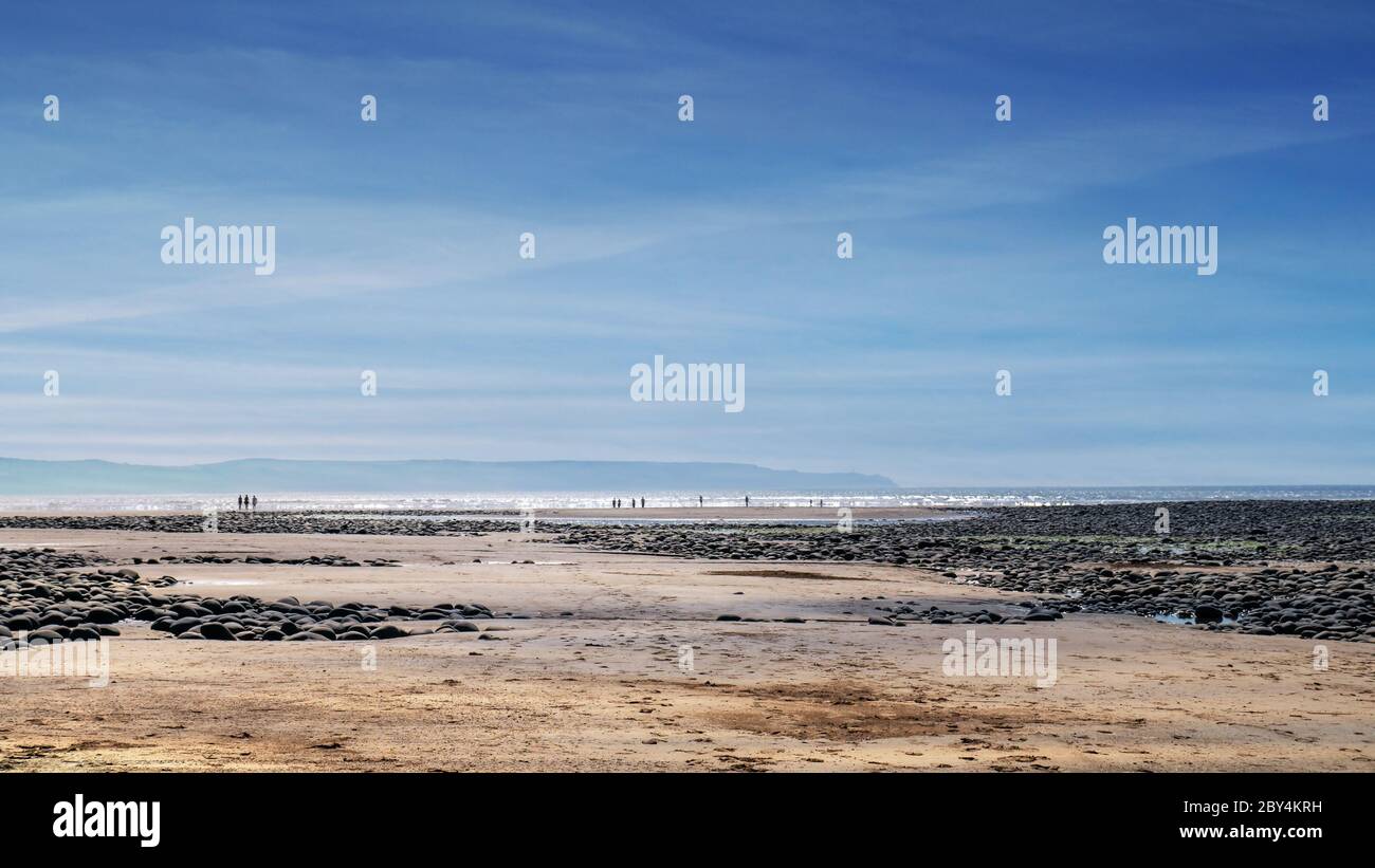 Vue sur la mer depuis Northam Burrows, North Devon, Royaume-Uni. Marée basse. Quelques personnes dans la distance dans les vagues. Estuaire de rivière spectaculaire. Banque D'Images