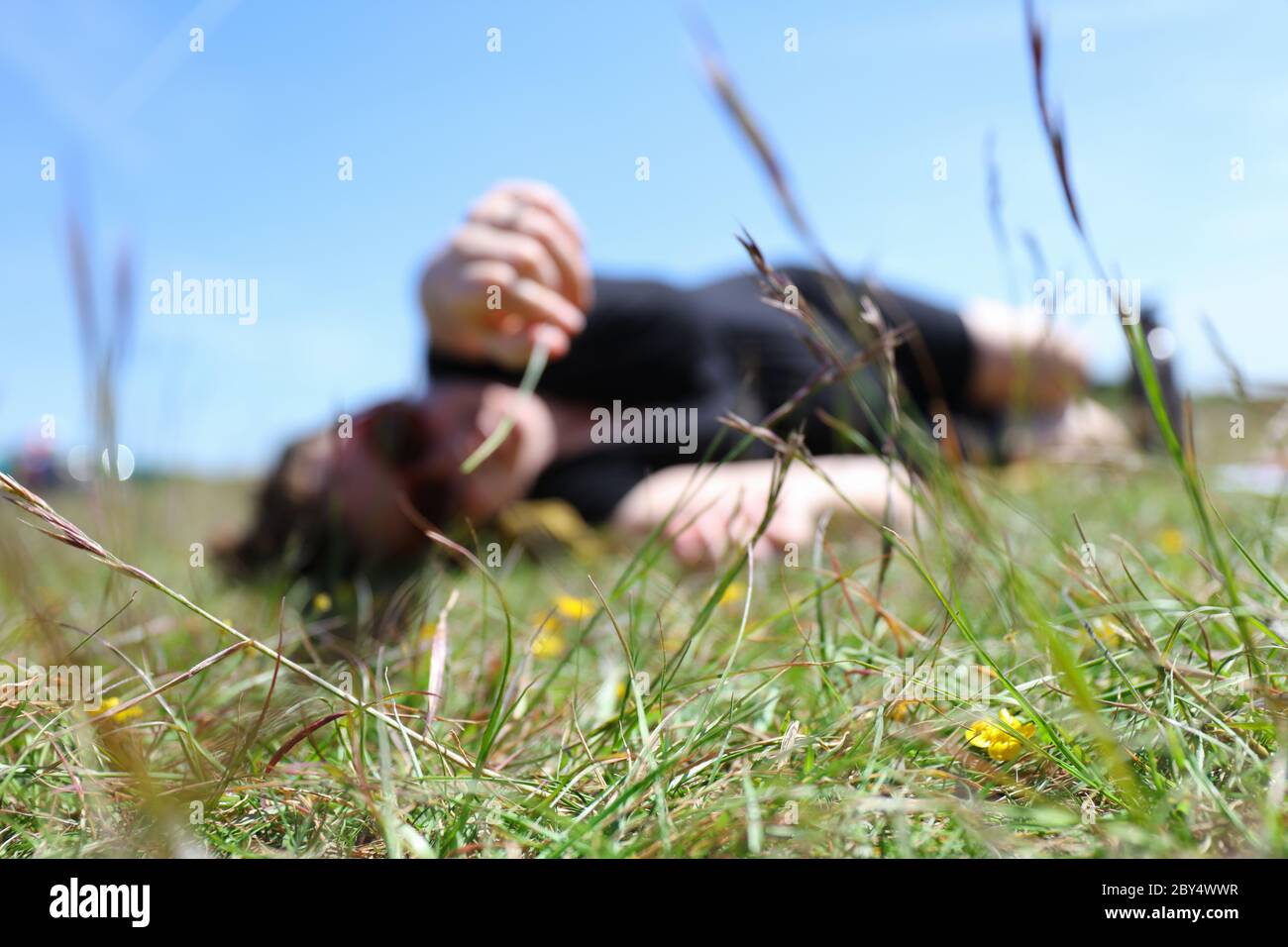 Jeune femme couché sur l'herbe avec le ciel bleu jouant avec l'herbe hors foyer Banque D'Images