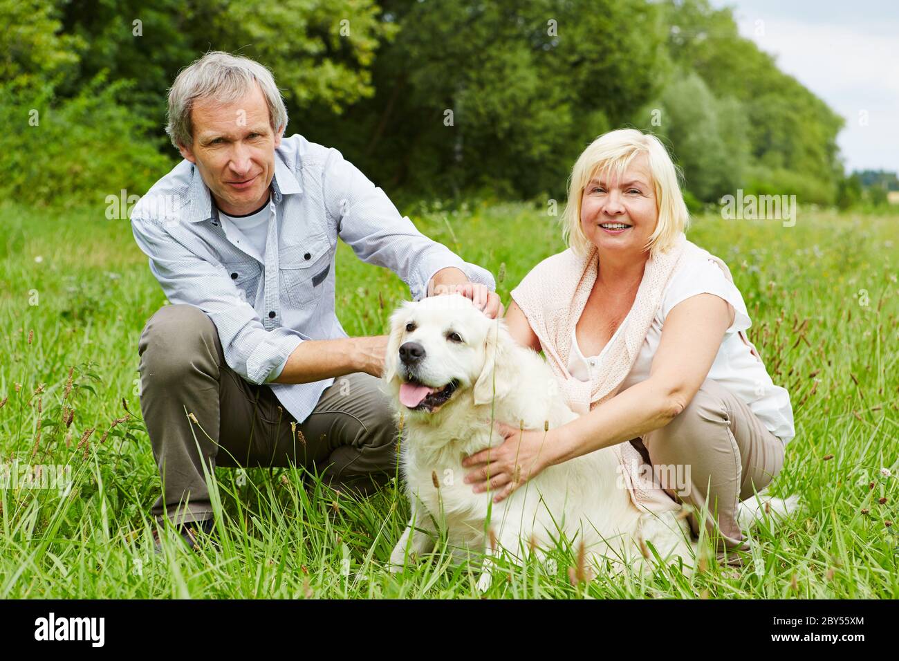 La vieille femme et le vieil homme câlin un chien de retriever doré dans le jardin Banque D'Images