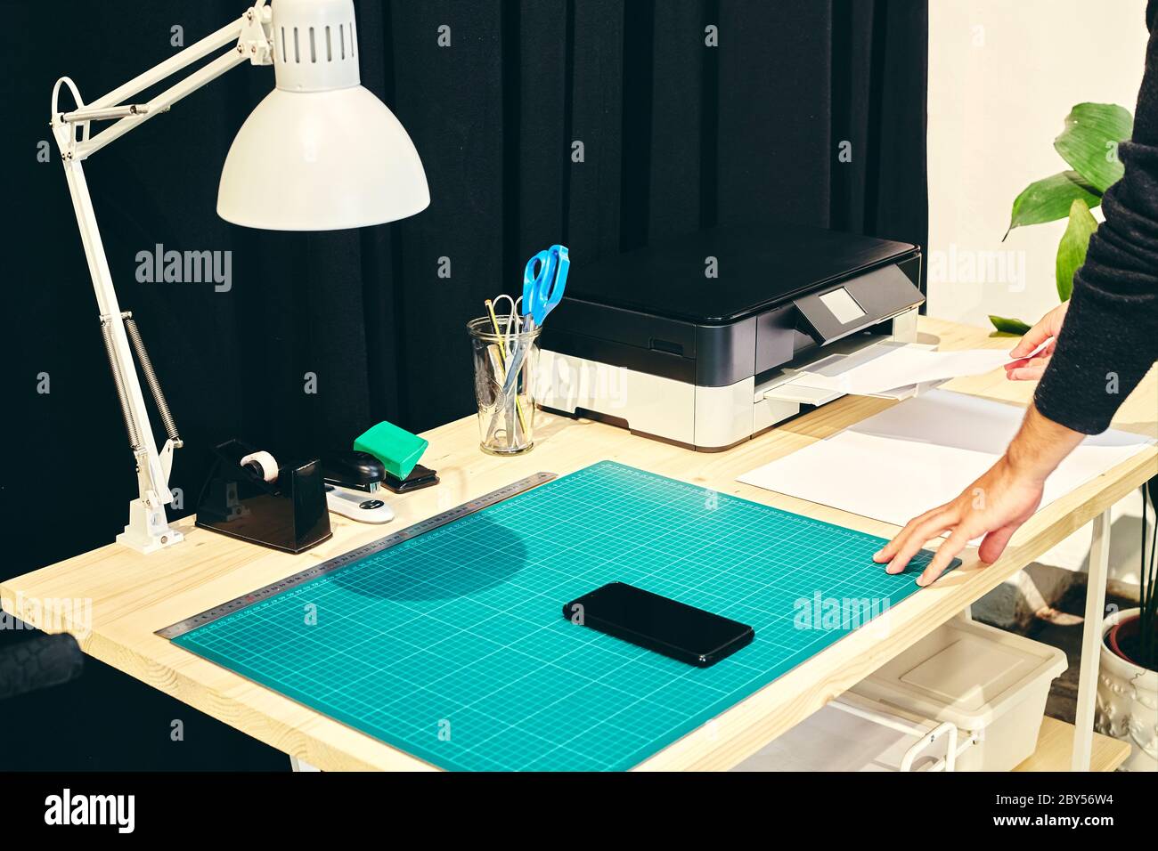 Espace de travail avec une personne à l'imprimante et un téléphone portable sur la table Banque D'Images