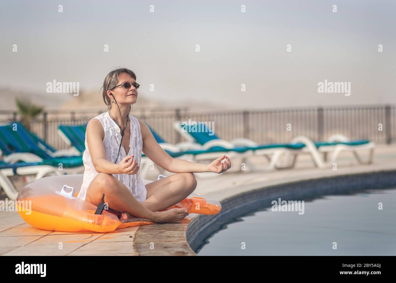 femme d'âge moyen appréciant ses vacances d'été au bord d'une piscine Banque D'Images