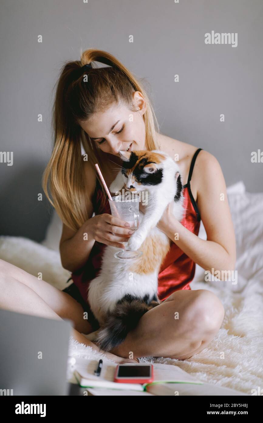 Femme gaie partageant un milkshake avec un chat Banque D'Images