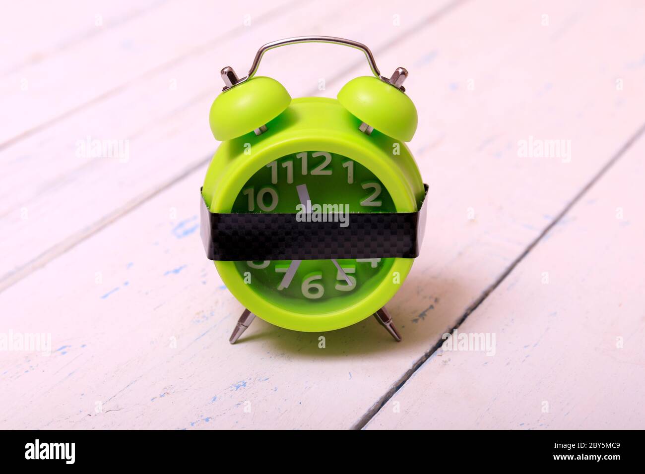 Réveil vert sur fond de bois blanc sorbde. Colle carbone sur le réveil pour le texte. Rappel. Espace pour la copie. Concept minimal. Banque D'Images