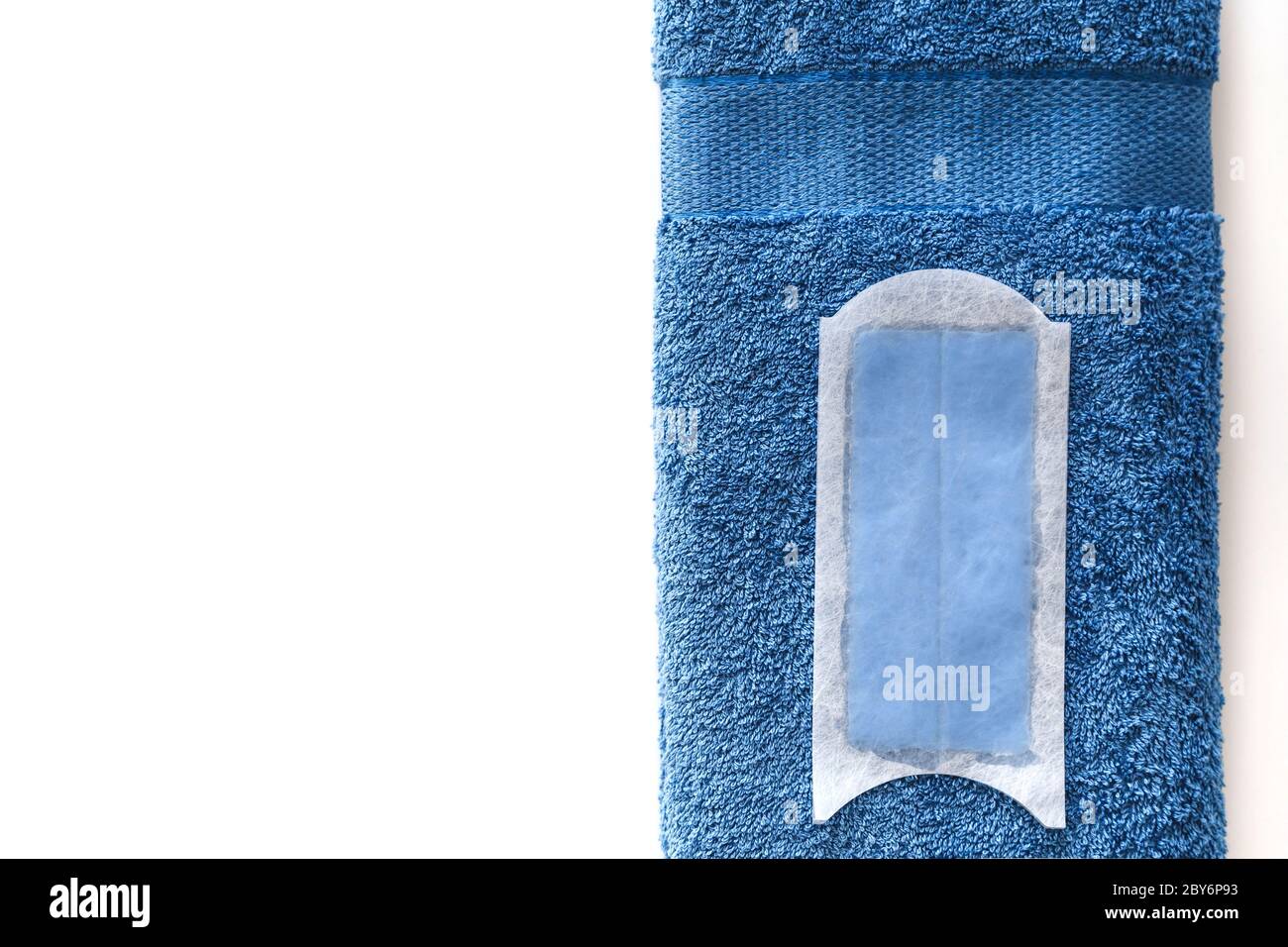 Bande de cire jetable pour l'épilation, sur une serviette en coton bleu isolée sur du blanc. Vue de dessus. Banque D'Images