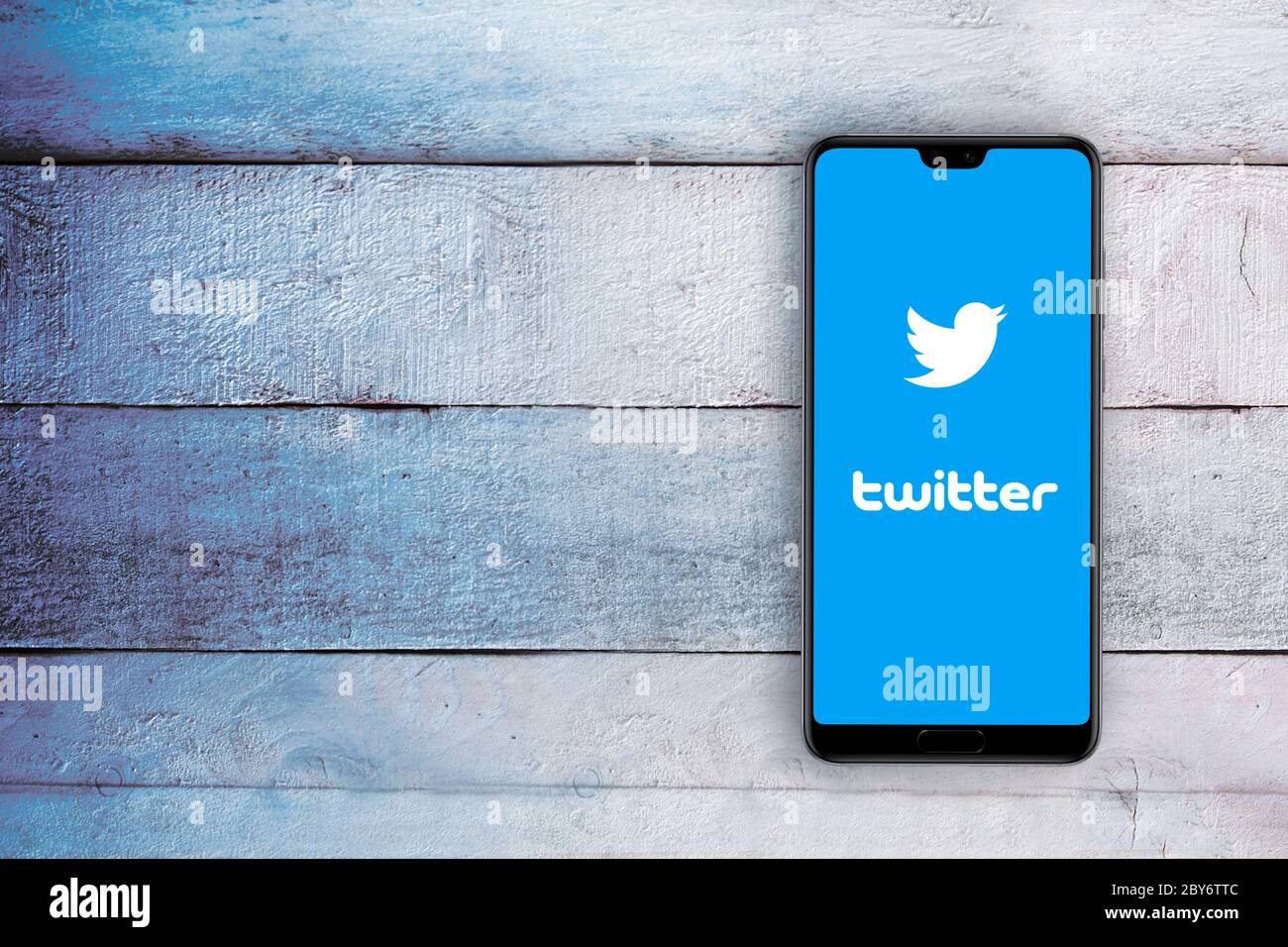Smartphone avec logo de l'application Twitter sur les réseaux sociaux à l'écran. Bureau en bois blanc, vue de dessus et espace de copie vide pour le texte de l'éditeur. Banque D'Images