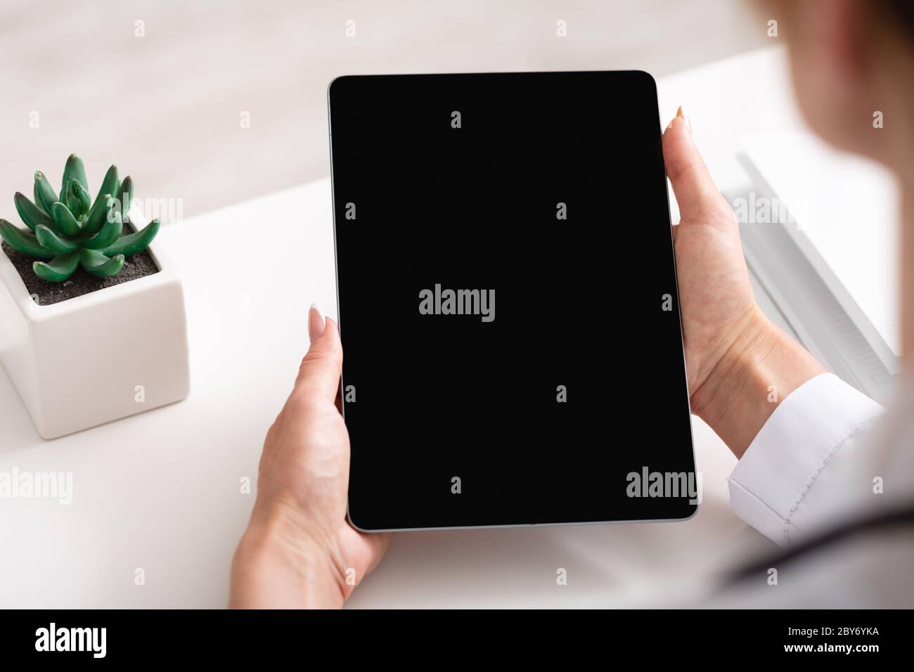Espace de travail et périphériques numériques. Tablette à main femelle avec écran vide Banque D'Images