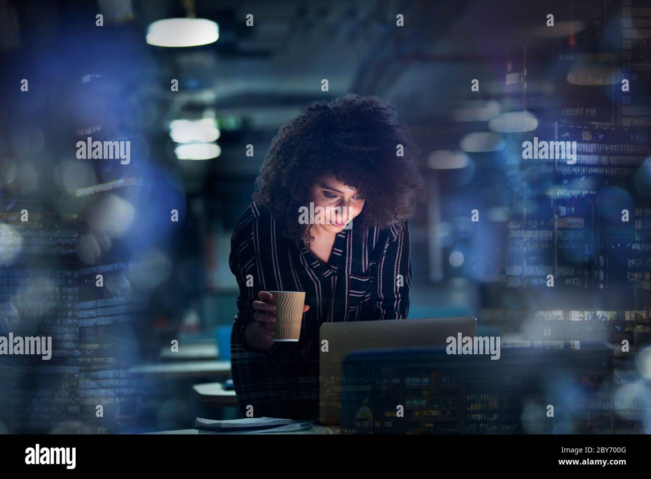 Femme d'affaires travaillant tard sur un ordinateur portable avec du café Banque D'Images