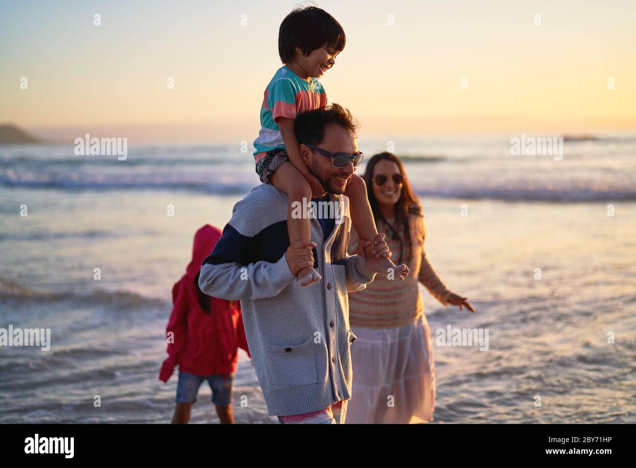Bonne famille barboter dans l'océan au coucher du soleil Banque D'Images