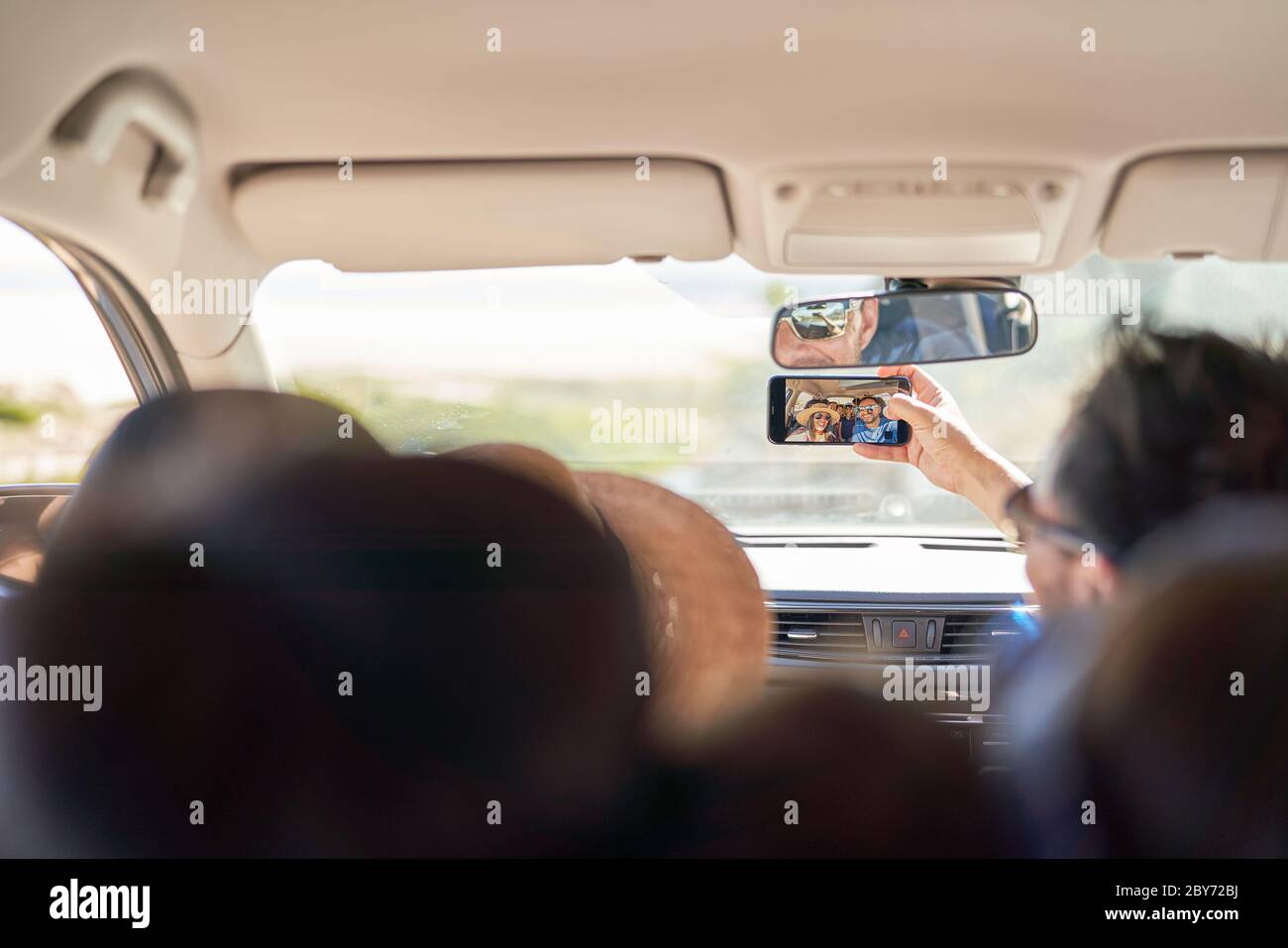 Famille prenant selfie avec un appareil photo téléphone dans la voiture Banque D'Images