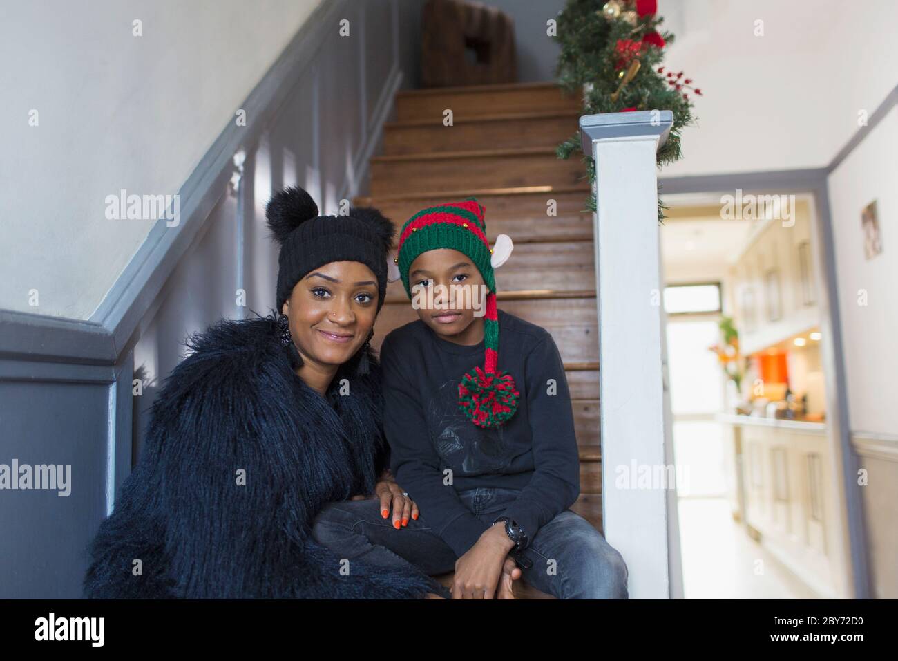 Portrait de mère et de fils dans des chapeaux de Noël sur les escaliers à la maison Banque D'Images