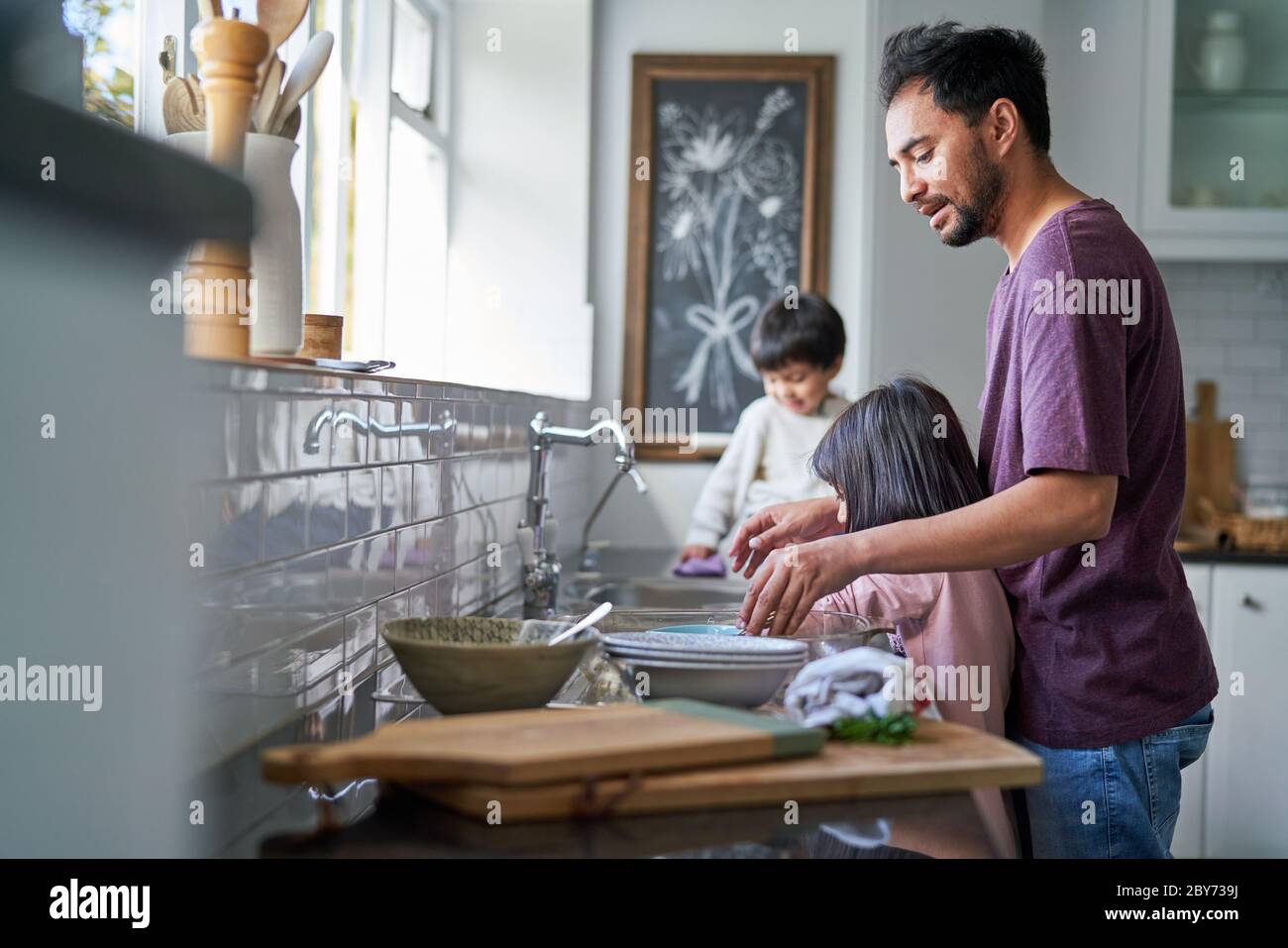 Père et enfants faisant des plats à l'évier de cuisine Banque D'Images