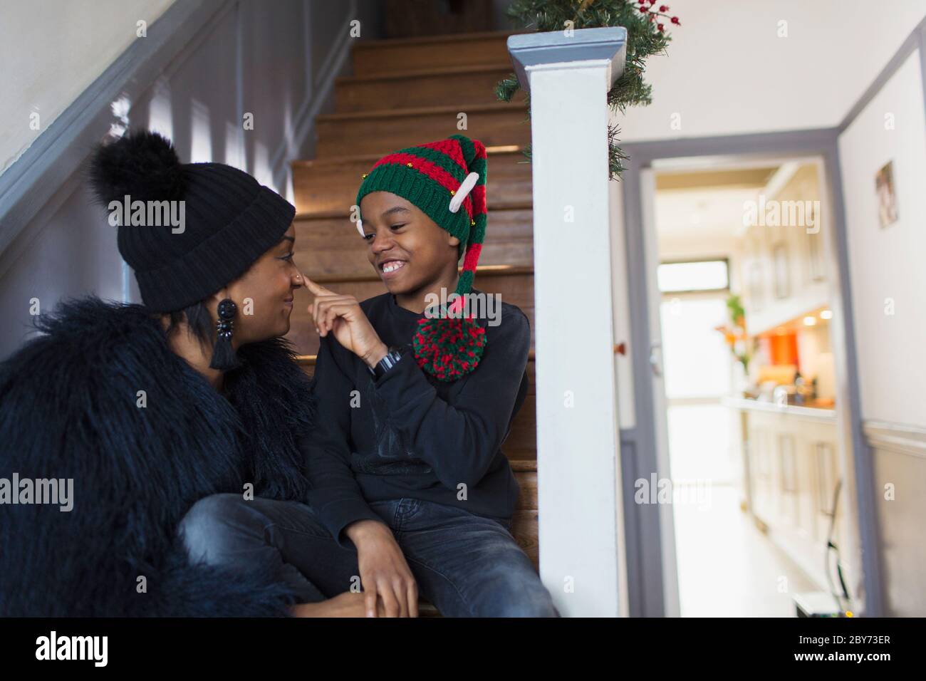 Mère et fils joueurs dans un chapeau de Noël sur les escaliers Banque D'Images