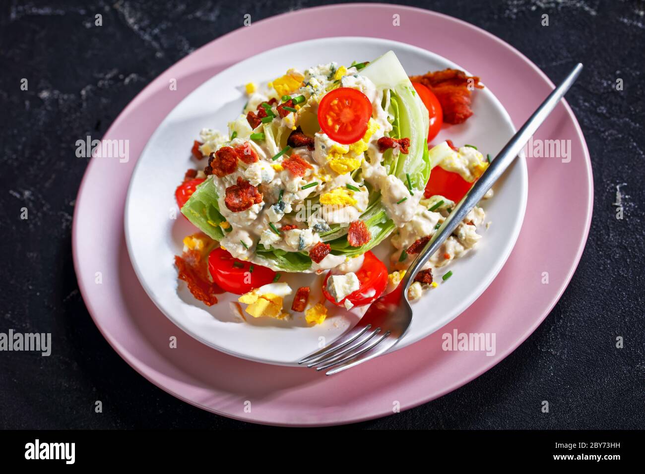 salade iceberg au fromage bleu, bacon croustillant, tomates cerises, œufs durs, ciboulette sur une table en béton, clo Banque D'Images